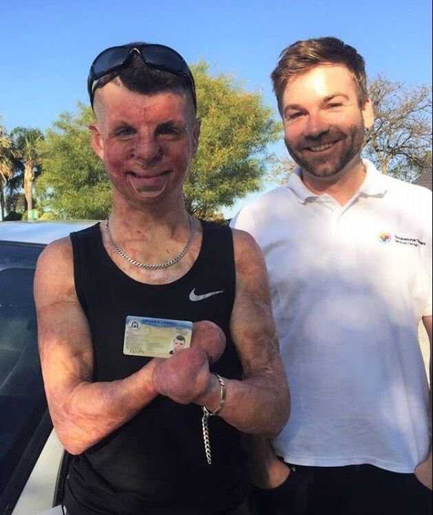 Client (left) holding his driver's licence and standing next to his Occupational Therapist (right)