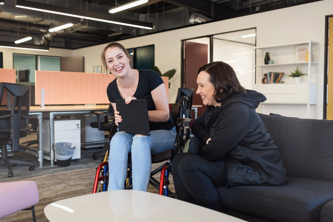 Picture of women seated in a wheelchair talking to a women seated on a couch